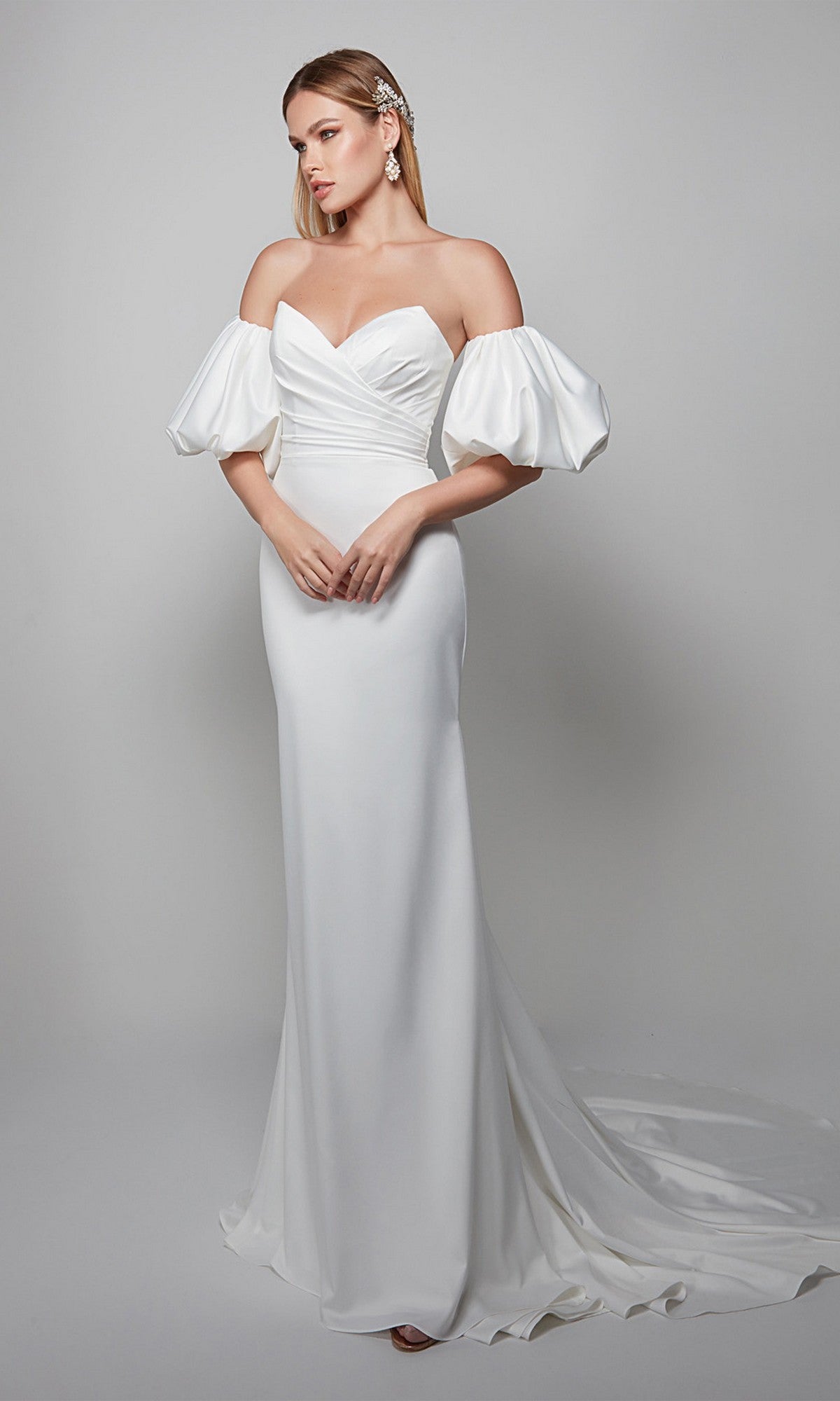 A woman models the Alyce 7056 long formal dress, featuring a white sweetheart neckline, off-the-shoulder puffed sleeves, fitted bodice, and a long train against a simple light background.